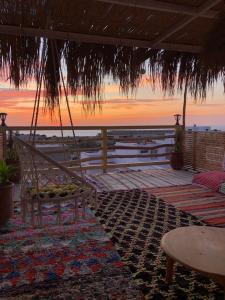 a porch swing with a view of the ocean at sunset at Natural Surf House in Tamraght Ouzdar