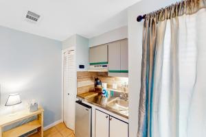 Una pequeña cocina con gabinetes blancos y un fregadero. en The Inn at St. Thomas Square #1202c, en Panama City Beach
