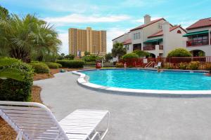 una piscina con 2 sillas blancas junto a un edificio en The Inn at St. Thomas Square #1202c, en Panama City Beach