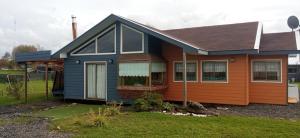 a house with an orange and blue at Casa chalet con tinaja in Pichil