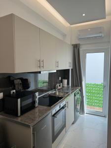 a kitchen with white cabinets and a large window at Cozy City Center Apartment in Rhodes Town