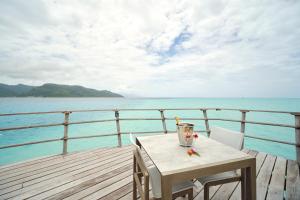 a table and chairs on a wooden deck overlooking the water at Le Taha'a by Pearl Resorts in Motu Tautau