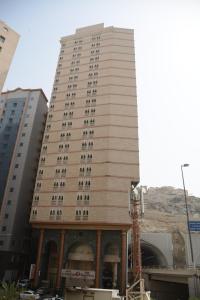 a tall white building with a tower at Wahet Al Deafah Hotel in Mecca
