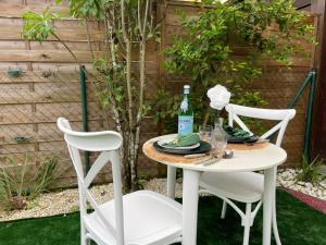 a table with two chairs and a bottle of wine at La parenthèse - Piscine - Plage - Jardin in Rémire-Camp