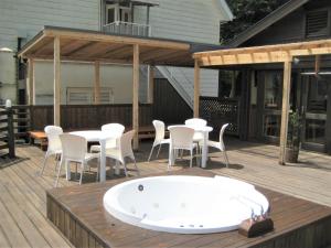 a hot tub on a deck with a table and chairs at Ernest House in Shimoda +5 photos