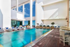 - une piscine dans un hôtel avec des chaises et une table dans l'établissement Marriott Executive Apartments Downtown, Abu Dhabi, à Abu Dhabi