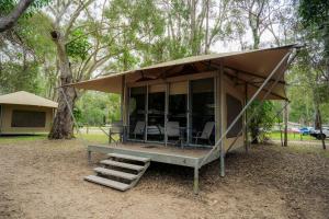 KangaROOMS Noosa Everglades YHA في Cootharaba: خيمة مع كراسي وطاولات في الحديقة