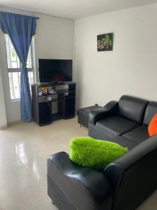 a living room with a black leather couch with a green pillow at Alojamiento Armenia in Armenia