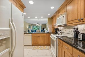 a kitchen with white appliances and wooden cabinets at 2024 Beach Wood in Amelia Island +42 photos