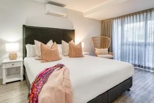 a bedroom with a large white bed and a window at Jacaranda Noosa in Noosa Heads