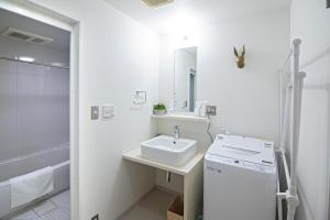 a white bathroom with a sink and a washing machine at 旅タイム・西長堀　駅まで徒歩6分　USJ電車8分 in Osaka