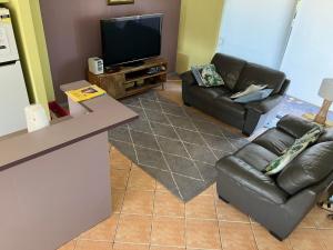 a living room with two leather couches and a flat screen tv at Nosie 2 in Sawtell