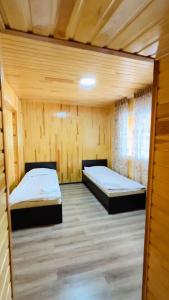 twee bedden in een kamer met houten wanden bij Отель Евразия in Cholpon-Ata