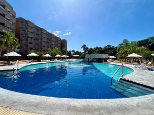 a large blue swimming pool with chairs and umbrellas at Barreirinhas Lençóis Flat Residence in Barreirinhas