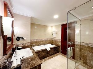 ein Bad mit einem Waschbecken und einer Dusche in der Unterkunft Rex Hotel in Ho-Chi-Minh-Stadt