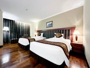 2 łóżka w pokoju hotelowym z drewnianą podłogą w obiekcie Rex Hotel w Ho Chi Minh