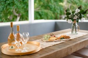 a table with two plates of food and wine glasses at Jacaranda Noosa in Noosa Heads
