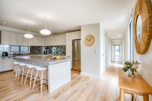 a kitchen with white cabinets and a large island with bar stools at Jacaranda Noosa in Noosa Heads