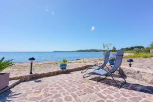 2 sedie sedute su un patio accanto all'acqua di Guest House MareLuna a Carloforte