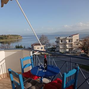 una mesa con 2 sillas y una botella de vino en el balcón en Angela's Seaview Apartment en Lefkandi Chalkidas
