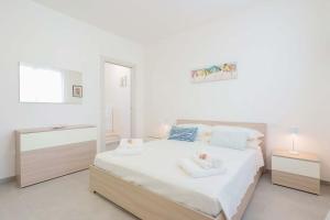 una camera da letto bianca con un letto e uno specchio di Guest House MareLuna a Carloforte