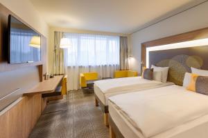 a hotel room with two beds and a television at Novotel München City Arnulfpark in Munich +165 photos