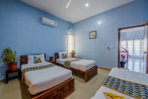 two beds in a room with blue walls at LikeMyVilla 3bedroom villa in Vānivilāsa Puram