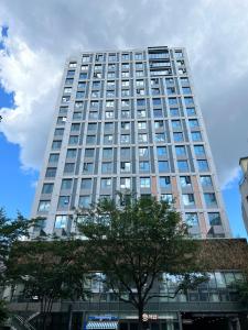 Un edificio alto con un árbol delante. en Apartment THE SHARE Myeongdong, en Seúl