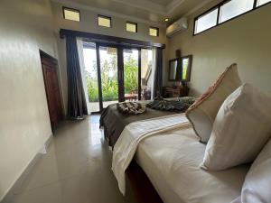 a bedroom with a bed and a large window at Nirwa Ubud Karma in Ubud