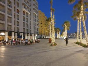 a person walking down a street with palm trees and lights at شالية مميز للإيجار Porto golf بورتو جولف مارينا in El Alamein