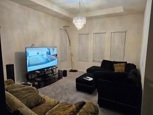ein Wohnzimmer mit einem Sofa und einem Flachbild-TV in der Unterkunft Troy@Kissimme in Kissimmee