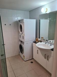 ein Badezimmer mit Waschmaschine und Waschbecken in der Unterkunft Manly Seabreeze in Sydney