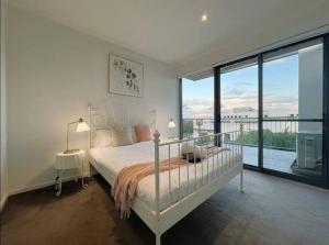 格伦韦弗利GW24-1 BATH 2 BR at The Glen with FREE Parking and Balcony的一间带床和大窗户的白色卧室
