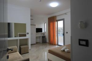 a room with a bed and a couch and a mirror at Hotel Villa Kapo Pool & Bar in Ksamil