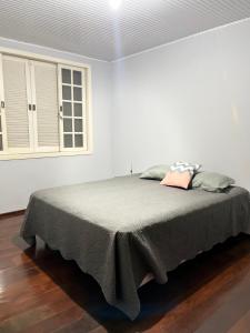 um quarto branco com uma cama com um cobertor cinzento em Mansao gloria em Joinville