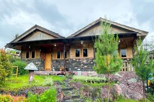 uma casa de madeira com um jardim em frente em RedDoorz at Kampung Istal Bogor em Jakarta