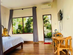 a bedroom with a bed and a table and windows at Mui Ne Garden Hotel and Kite School in Mui Ne