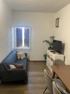 a living room with a blue couch and a television at Carob apartment - Balcony view of the sea & Bisevo in Komiža