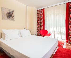 a bedroom with a large white bed and a red chair at Pelister Skopje in Skopje