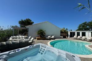 a swimming pool with chairs and a hot tub at La Perle Rose Villa Standing 5 étoiles avec piscine jacuzzi et superbe vue in Aigues-Mortes