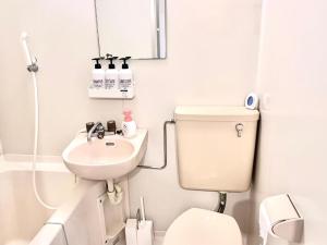 a white bathroom with a toilet and a sink at Ikebukuro Sugamo 駅近 A4 in Tokyo +2 photos