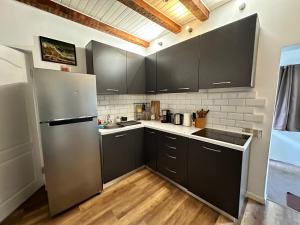 a kitchen with black cabinets and a stainless steel refrigerator at Interbelic house with courtyard and terrace in Bucharest