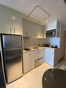 una cocina con nevera de acero inoxidable y armarios blancos en Ocean View Studio Apt - Surfer's Paradise, en Gold Coast
