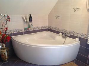 a large white tub in a bathroom with tiles at Noclegi Pod Borkiem in Szypliszki