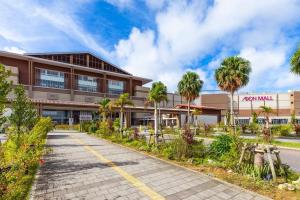 a building with palm trees in front of it at LOA Chatan Resort in Chatan