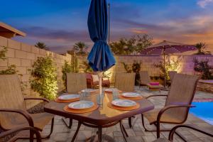 a wooden table with chairs and an umbrella on a patio at Resort style Retreat ! New Pool , Spa and Game room in Coachella