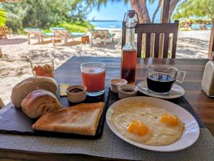 un tavolo con colazione a base di uova, pane e bevande di Ocean Lodge Kite & Windsurf a Antsiranana