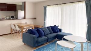 ein Wohnzimmer mit einem blauen Sofa und einem Tisch in der Unterkunft Sunshoen Akaishibeach in Hirakubo