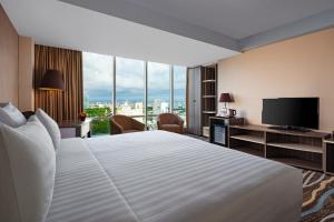 um quarto de hotel com uma cama grande e uma televisão de ecrã plano em Swiss-Belhotel Makassar em Makassar
