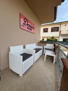 a patio with wicker chairs and a sign on a building at DENIA'S HOME in SantʼEufemia Lamezia